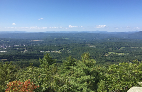 A panoramic view of lush green valleys and distant mountains under a clear blue sky.