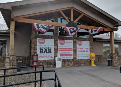 Exterior of a sports bar with banners promoting specials and a welcome sign for hunters.