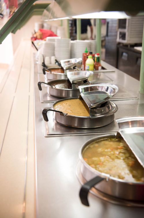 A buffet line featuring various soups and sauces in metal containers on a stainless steel counter.