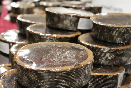 A close-up of stacked, round chocolate desserts wrapped in clear plastic, showcasing their glossy surface.