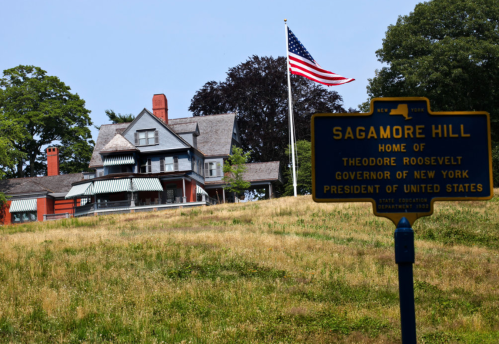 Historic Sagamore Hill, home of Theodore Roosevelt, with an American flag and a sign marking its significance.