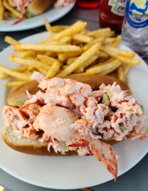 A lobster roll overflowing with lobster meat, served with a side of golden French fries.