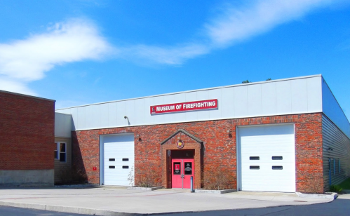 Exterior of the Museum of Firefighting, featuring a brick facade and large garage doors under a clear blue sky.