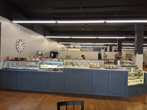 A modern bakery interior featuring a display case with pastries and a clock on the wall.