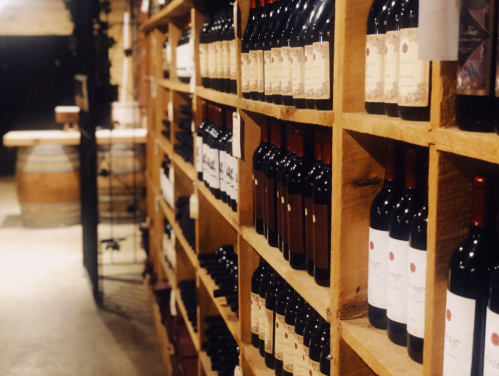 A wooden wine rack filled with bottles of red wine in a dimly lit cellar.