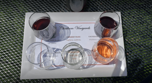 A tray with six wine glasses filled with different wines, alongside a menu from Chatham Vineyards.