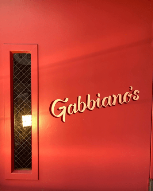 A red wall with a window and the sign "Gabbiano's" in elegant white lettering.