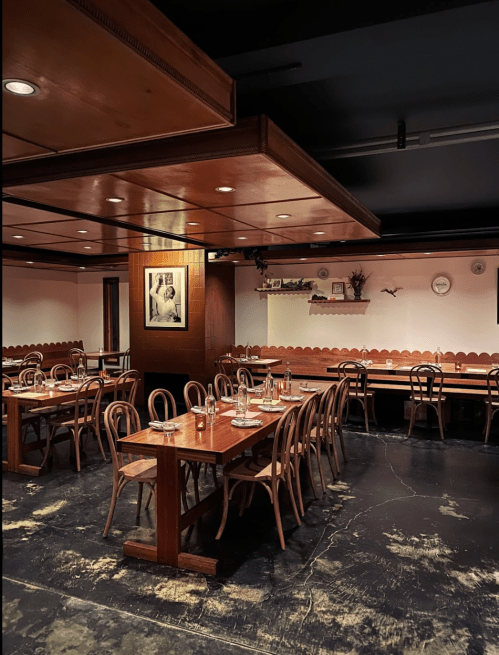 Cozy restaurant interior with wooden tables, chairs, and a framed photo on the wall, softly lit ambiance.