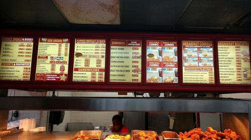Menu board displaying various meal options, including family meals, sandwiches, dinners, and breakfast items.
