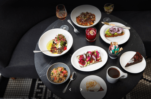 A table set with various colorful dishes, including salads, desserts, and drinks, arranged on a dark surface.