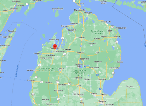 Map showing Traverse City, Michigan, highlighted in red, surrounded by green areas and nearby towns.