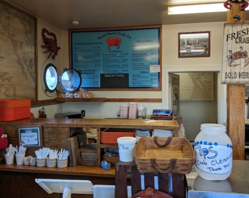 Interior of a seafood restaurant with a menu board, crab decorations, and a counter with utensils and containers.