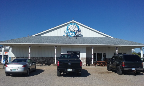 Exterior of a building with a sign reading "McCoole," featuring parked trucks and a clear blue sky.