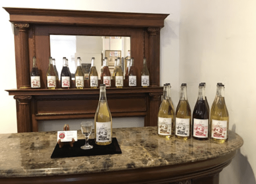A display of various bottled beverages on a marble counter, with a mirror and a tasting glass in front.