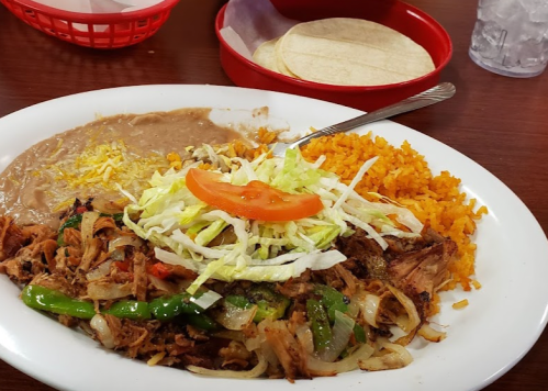 A plate of Mexican food featuring rice, refried beans, seasoned meat with vegetables, lettuce, tomato, and tortillas.