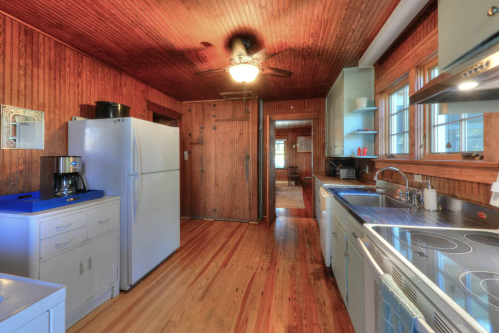 A cozy kitchen with wooden walls, a white refrigerator, and modern appliances, featuring a warm, inviting atmosphere.