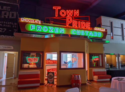 A retro-style ice cream shop with neon signs reading "Town Pride Frozen Custard" and "Chocolate Vanilla."