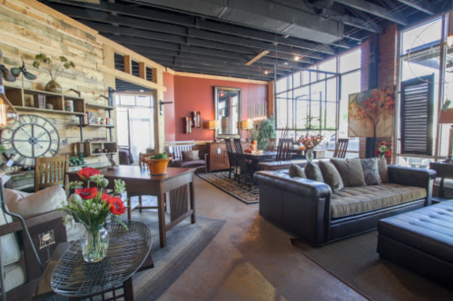 Cozy, modern living space with a mix of wood and leather furniture, large windows, and decorative plants.