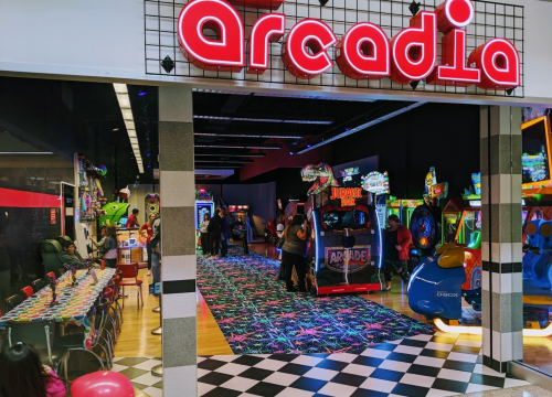 Brightly lit arcade entrance with colorful games and a vibrant carpet, inviting visitors to enjoy various arcade activities.