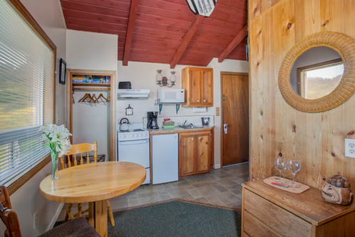 Cozy kitchen area with wooden cabinets, a round table, and a small dining space, featuring natural light and rustic decor.