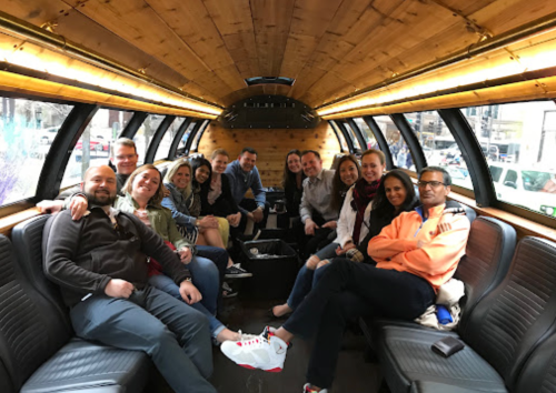 A group of people sitting inside a stylish bus with wooden interior, smiling and enjoying each other's company.
