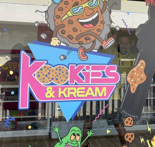 Colorful sign for "Kookies & Kream" featuring a cartoon cookie character and playful graphics.