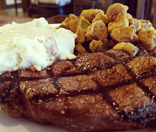 A plate featuring a grilled steak, creamy mashed potatoes, and a side of fried okra.