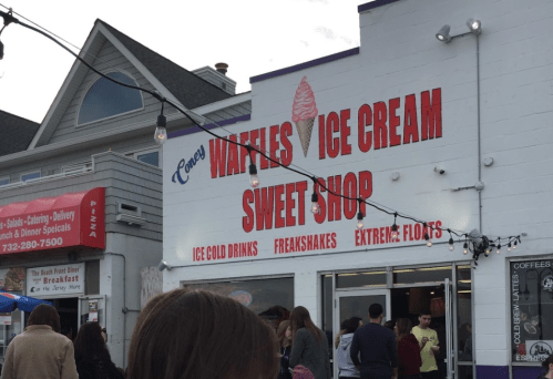 A storefront with a sign reading "Waffles Ice Cream Sweet Shop," featuring ice drinks, freakshakes, and floats.