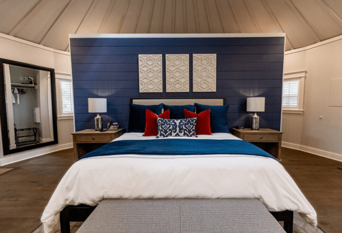 Cozy bedroom with a blue accent wall, a king-sized bed, decorative pillows, and stylish lamps on nightstands.