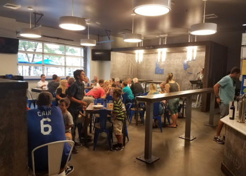 A busy restaurant interior with families and groups dining at tables, featuring modern decor and bright lighting.