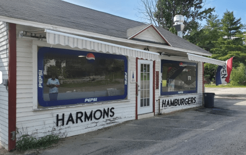 A small, white building with "Harmons Hamburgers" signage and Pepsi advertisements on the windows.