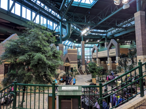 Interior view of a spacious retail store with greenery, high ceilings, and multiple sections for shopping and activities.