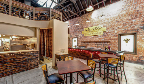 Cozy restaurant interior with exposed brick walls, wooden bar, and tables, featuring warm lighting and a welcoming atmosphere.