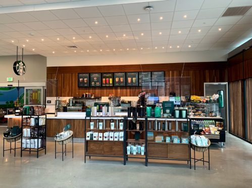 A modern Starbucks interior featuring a counter, display cases, and shelves with various products.
