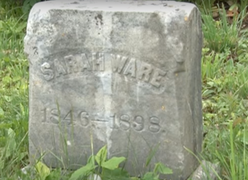 A weathered gravestone reading "Sarah Ware 1846-1898," surrounded by grass and foliage.