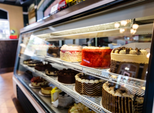 A display case filled with various colorful cakes, showcasing different flavors and designs.
