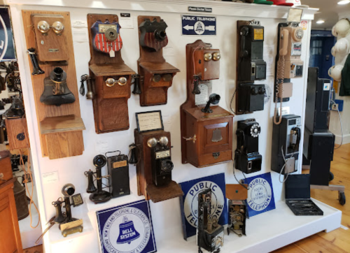 A display of vintage telephones on a wall, showcasing various styles and designs from different eras.