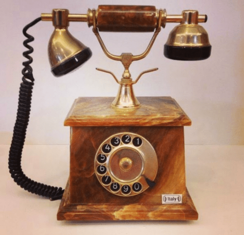 Vintage rotary phone with a marble-like base and metal accents, featuring a coiled cord and a classic design.