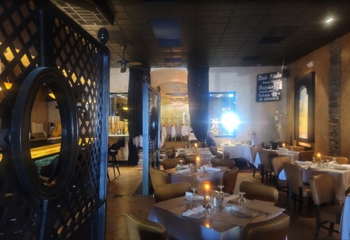 Cozy restaurant interior with tables set for dining, warm lighting, and a welcoming atmosphere.