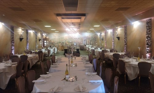 Elegant restaurant interior with tables set for dining, soft lighting, and a mural of a scenic landscape on the wall.