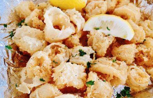 A plate of crispy fried calamari garnished with lemon wedges and parsley.