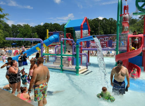 A vibrant water park scene with children playing, colorful slides, and families enjoying the pool on a sunny day.