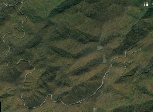 Aerial view of winding rivers through dense green forests and hilly terrain.