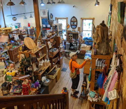 A person browsing in a cozy, rustic gift shop filled with various crafts and decorations.