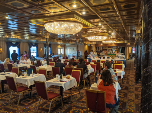 Elegant restaurant interior with chandeliers, tables set for dining, and guests enjoying their meals.