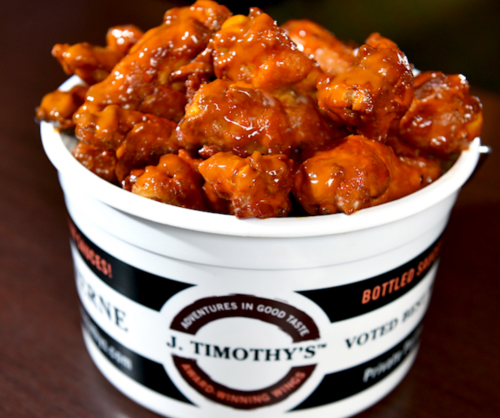 A bucket filled with glazed chicken wings, showcasing a rich, shiny sauce.