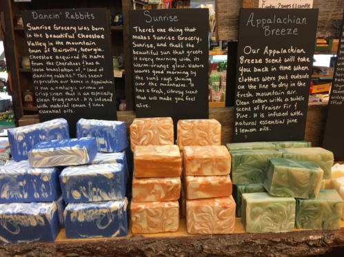 Display of colorful handmade soaps with descriptions, including "Dancin' Rabbits," "Sunrise," and "Appalachian Breeze."