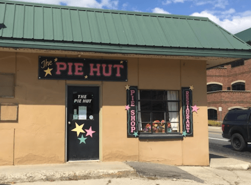 Exterior of "The Pie Hut," featuring a green roof, colorful star decorations, and a sign for the pie shop and restaurant.