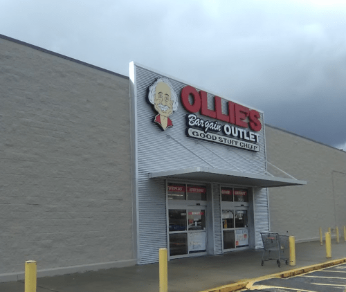 Exterior of Ollie's Bargain Outlet store with a sign featuring a smiling character and the slogan "Good Stuff Cheap."