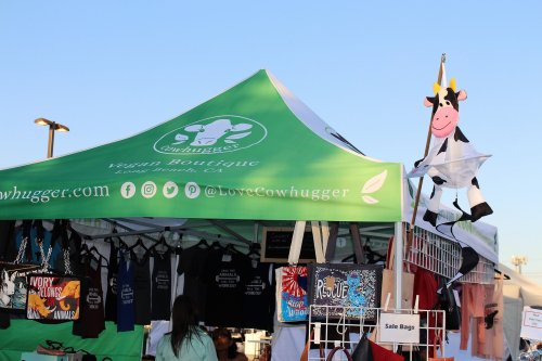 A green tent for "Cowhugger Vegan Boutique" with a cow decoration and various merchandise displayed.